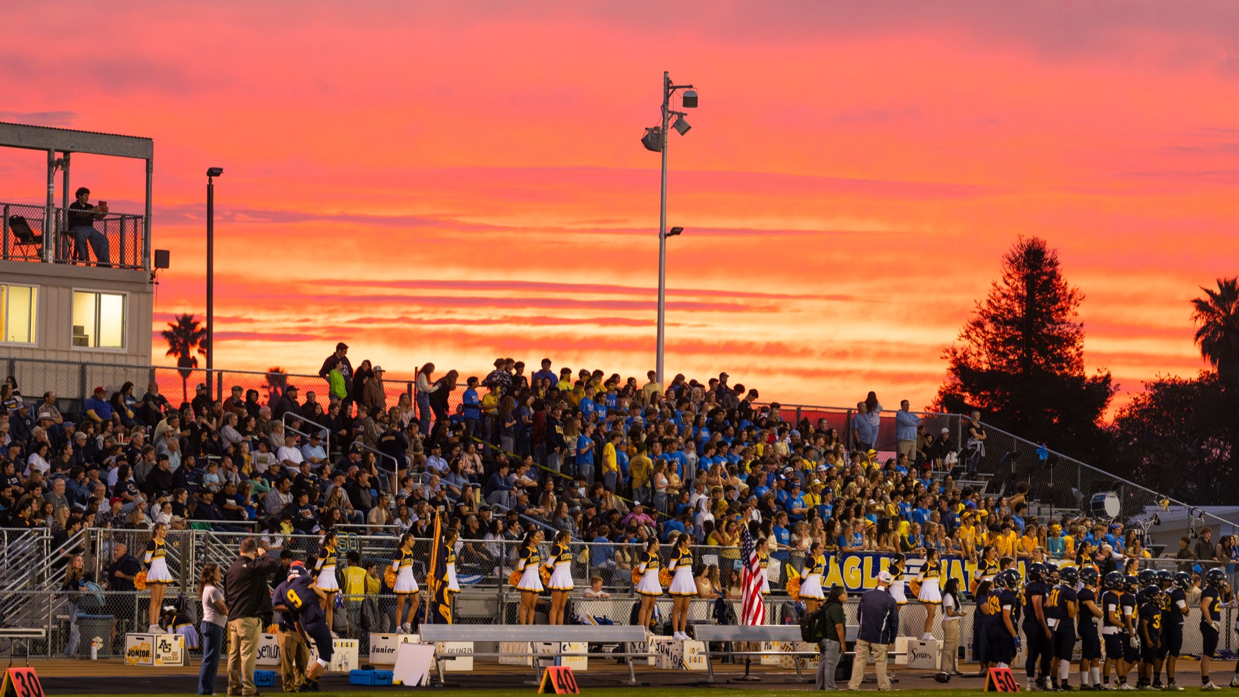 Arroyo Grande fans and stadium lights beneath a sunset before the home opener against Paso Robles