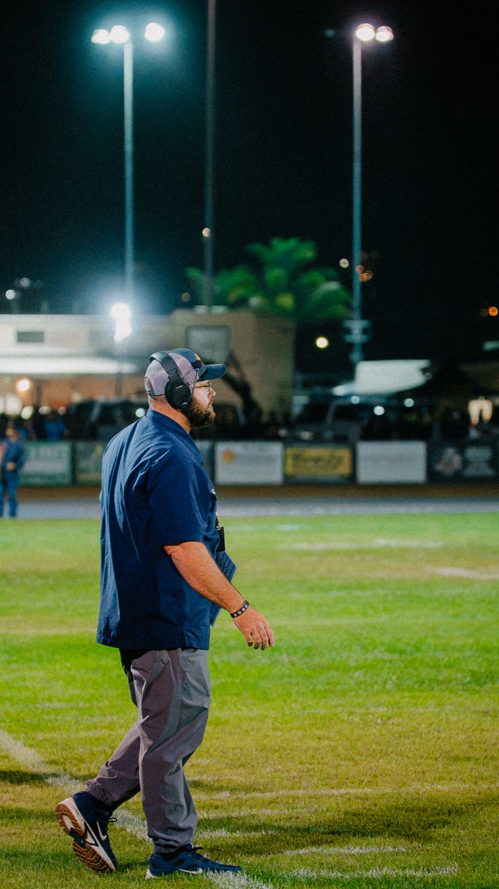 An Arroyo Grande coach walks the sideline alone under the stadium lights