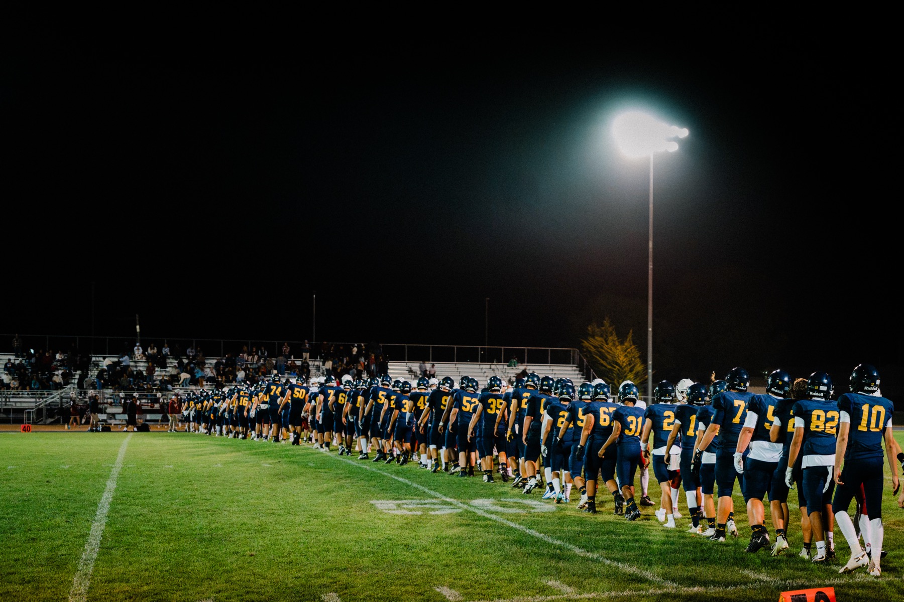 The Arroyo Grande football team lined up along the sideline under the lights