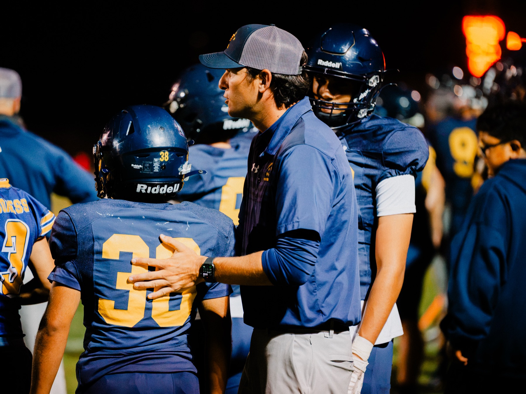 An Arroyo Grande coach talks with a player on the sideline during the game