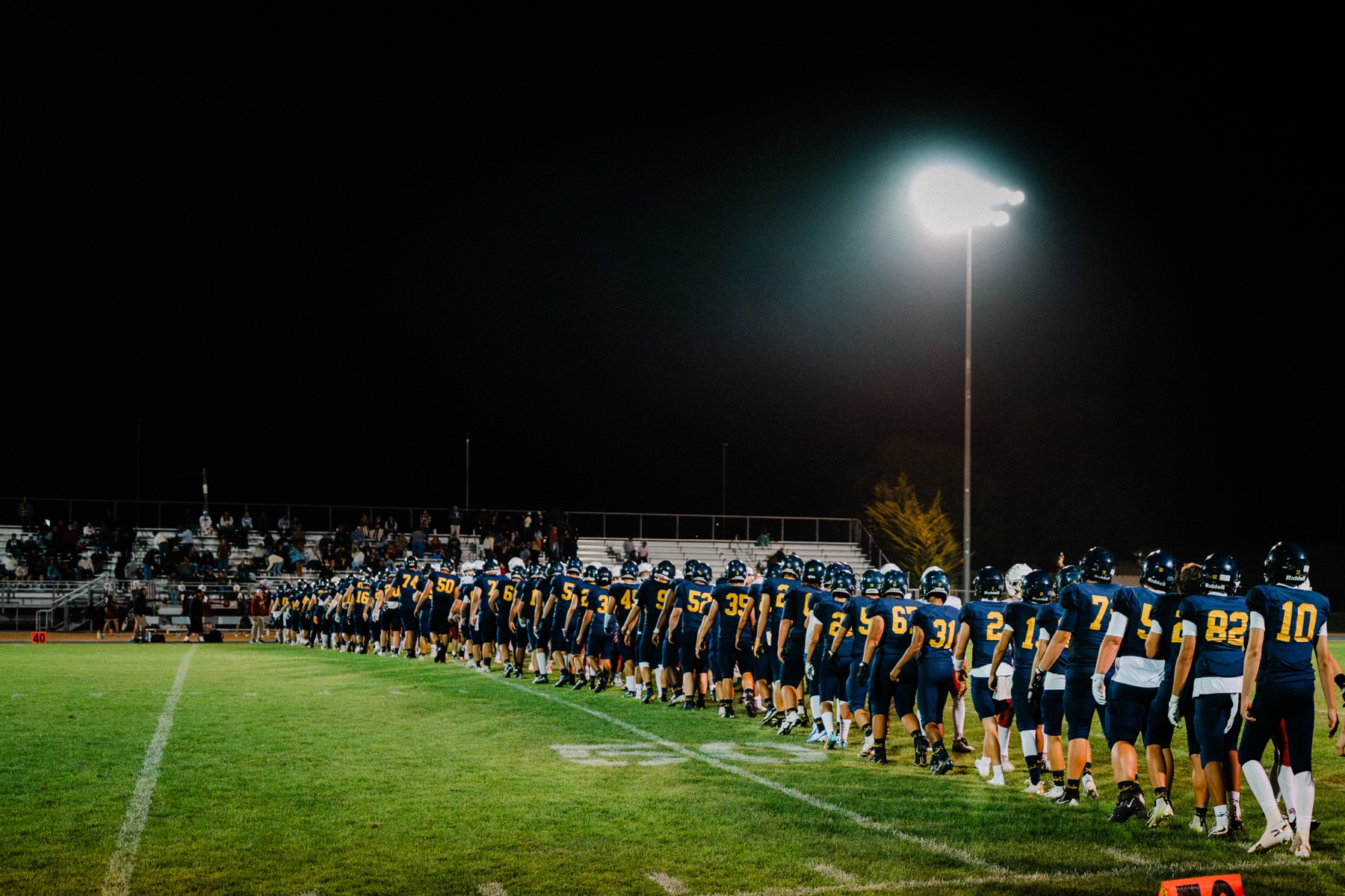 The Arroyo Grande football team lined up along the sideline under the stadium lights