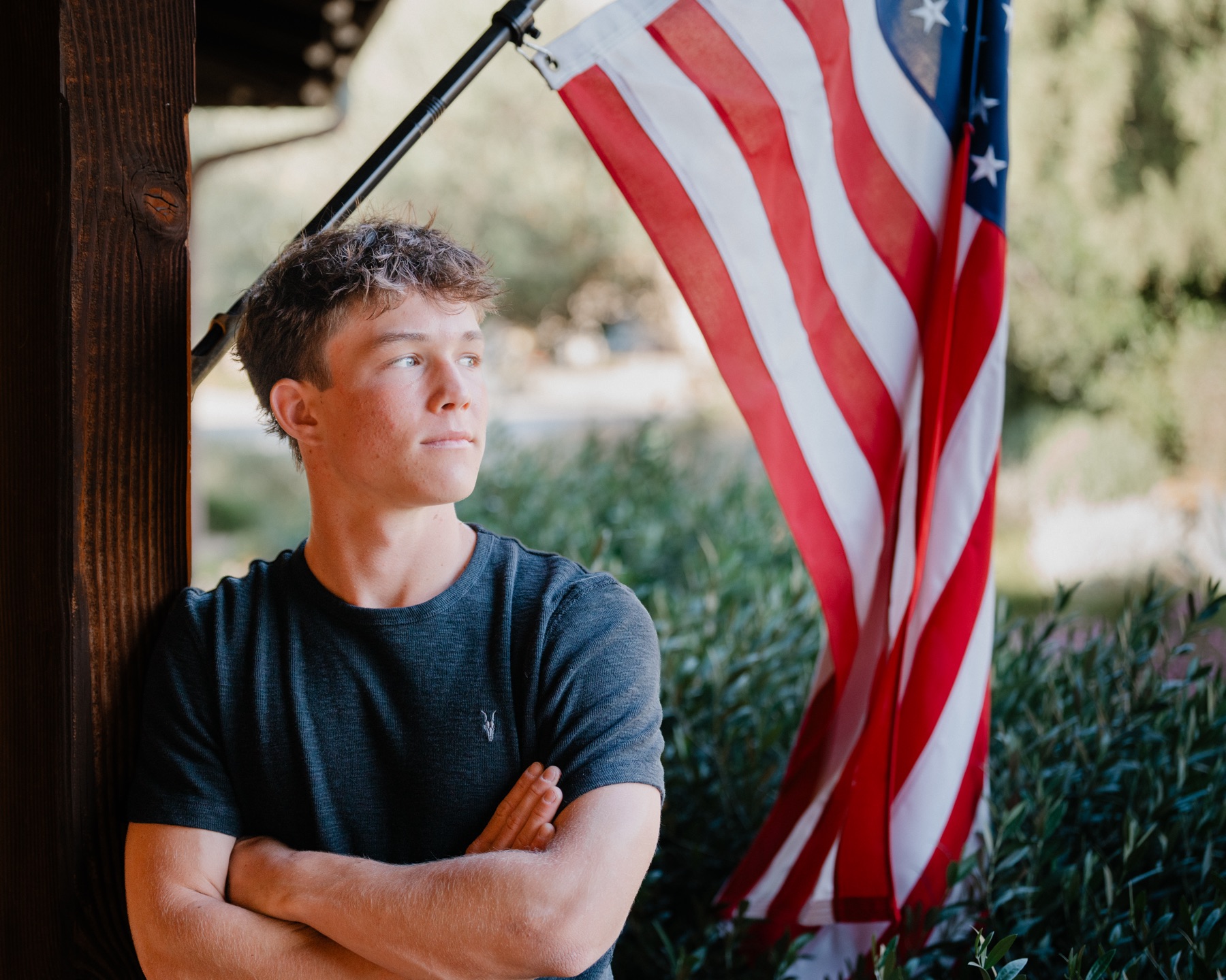 Senior portrait on a porch beside an American flag — Central Coast senior photographer