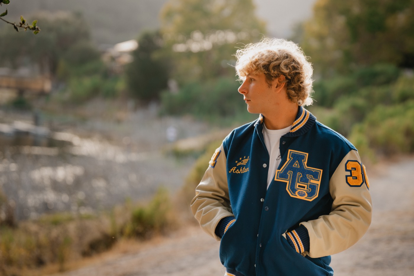 Senior portrait in a varsity jacket, golden hour profile — Central Coast senior photographer