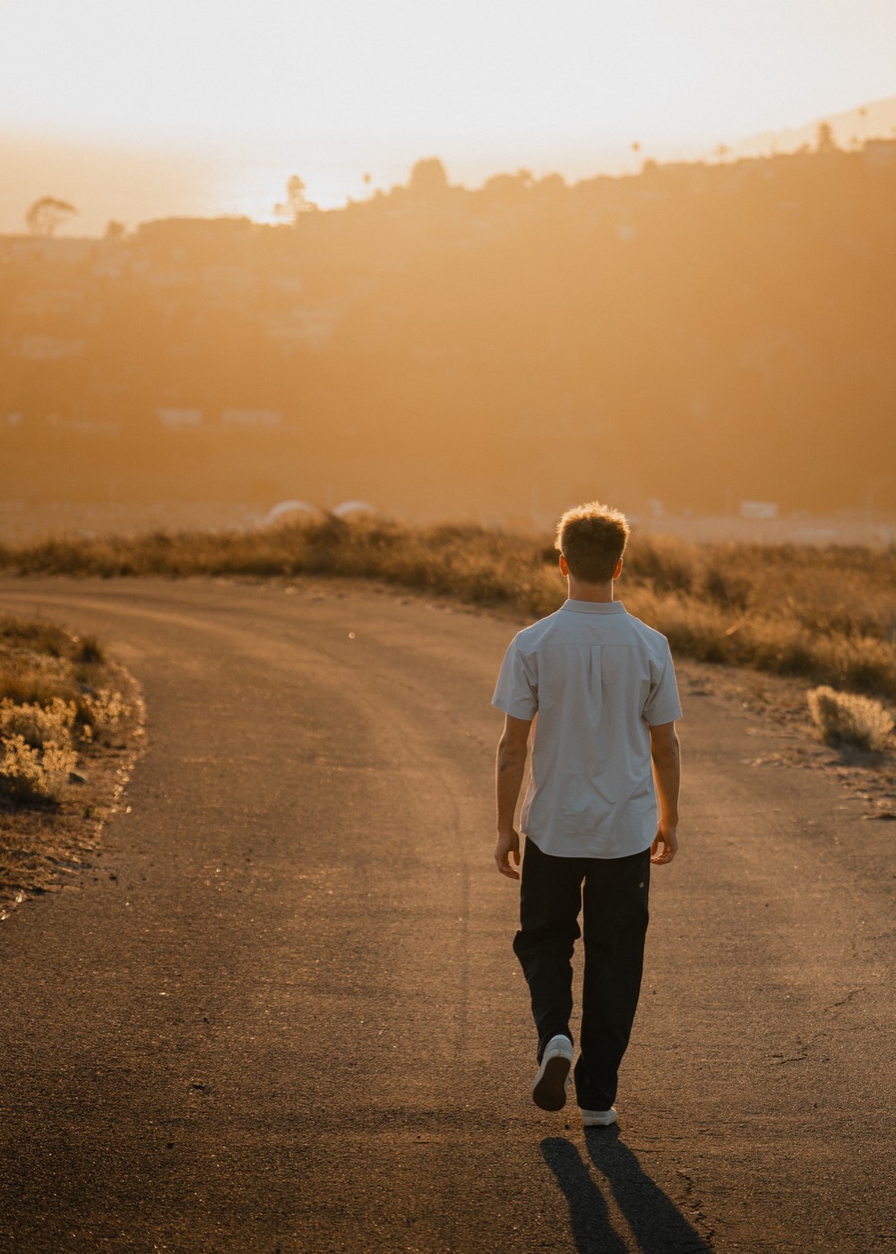 Senior portrait walking into golden hour light along the coast — Central Coast senior photographer