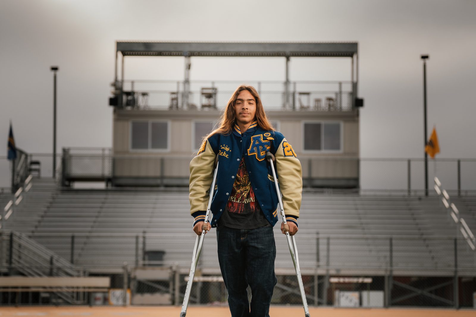 Senior boy on crutches walking across football field, Arroyo Grande stadium