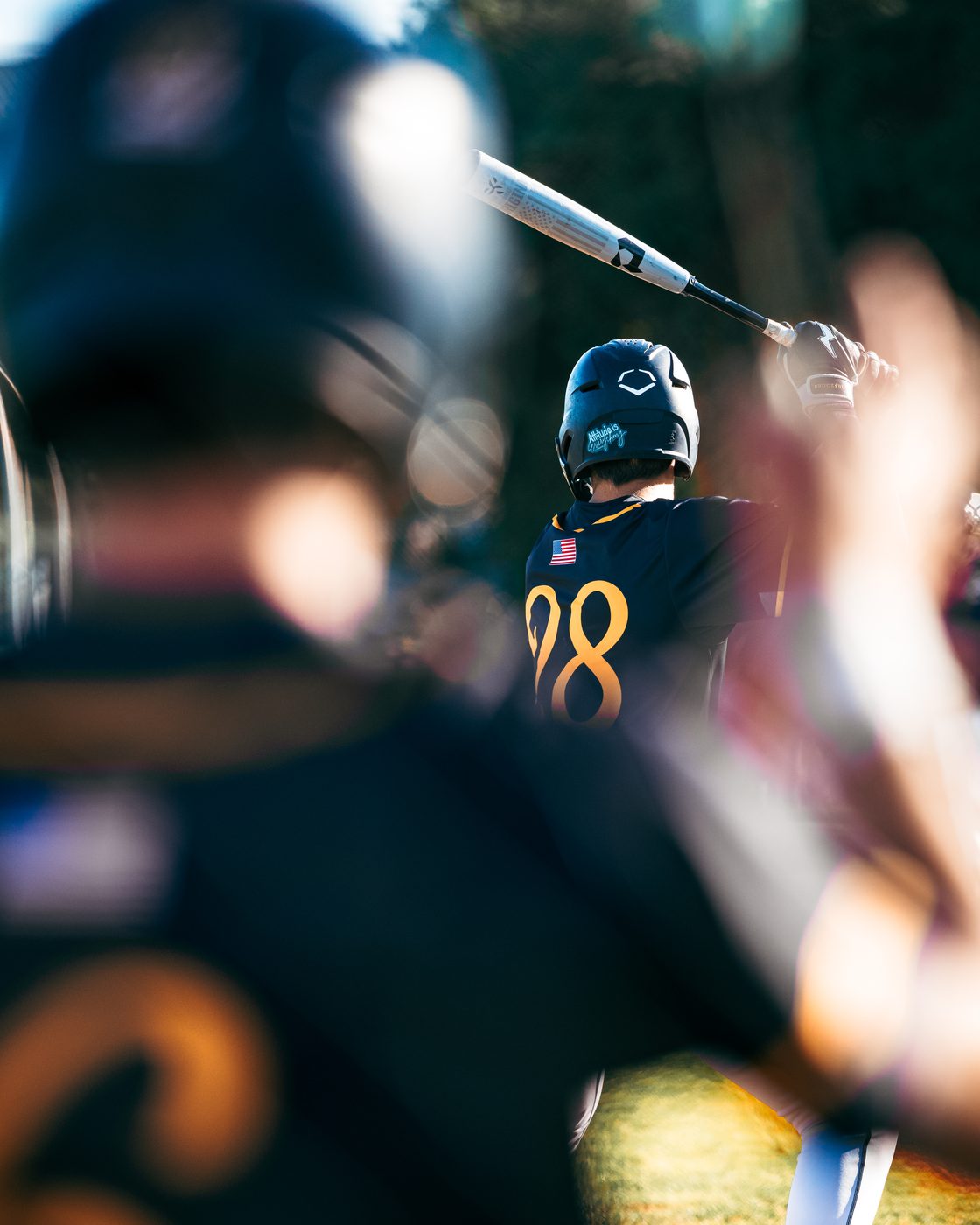 Baseball batter at golden hour, through-the-fence perspective