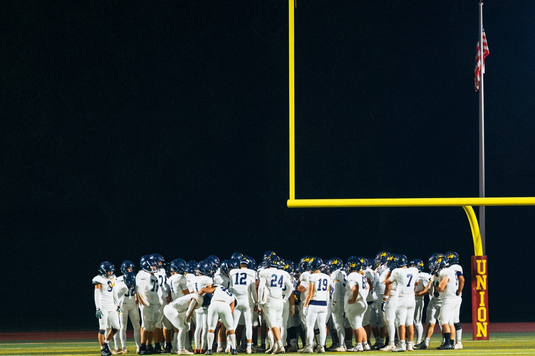 Football team huddled under goalpost at night