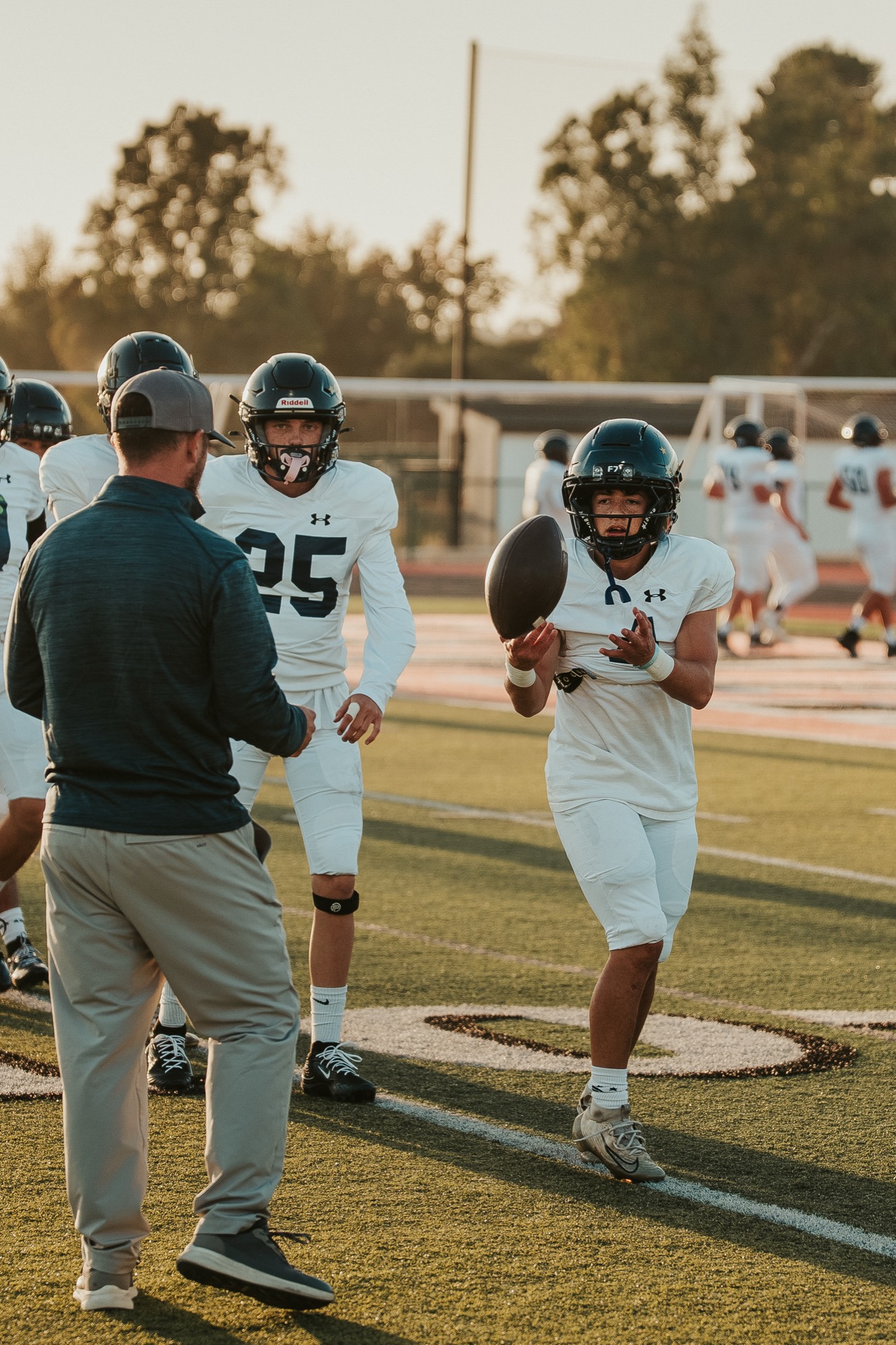 A coach handing off the ball to an Arroyo Grande player during a drill